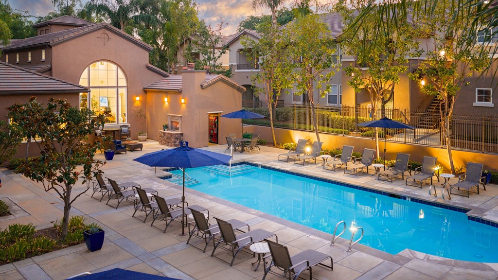 A pool surrounded by chairs and umbrellas.