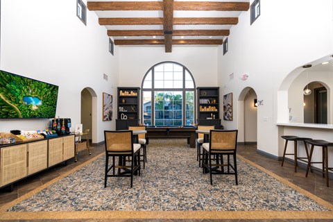 A living room with a large rug and a TV on the wall.