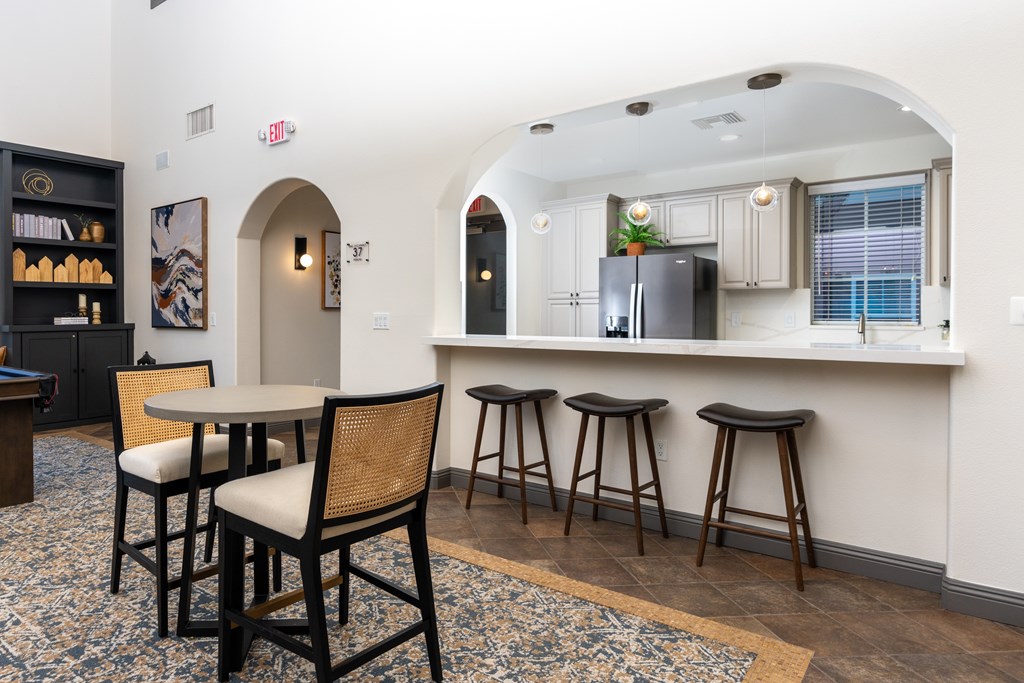 A kitchen with a bar area featuring a black fridge and bar stools.