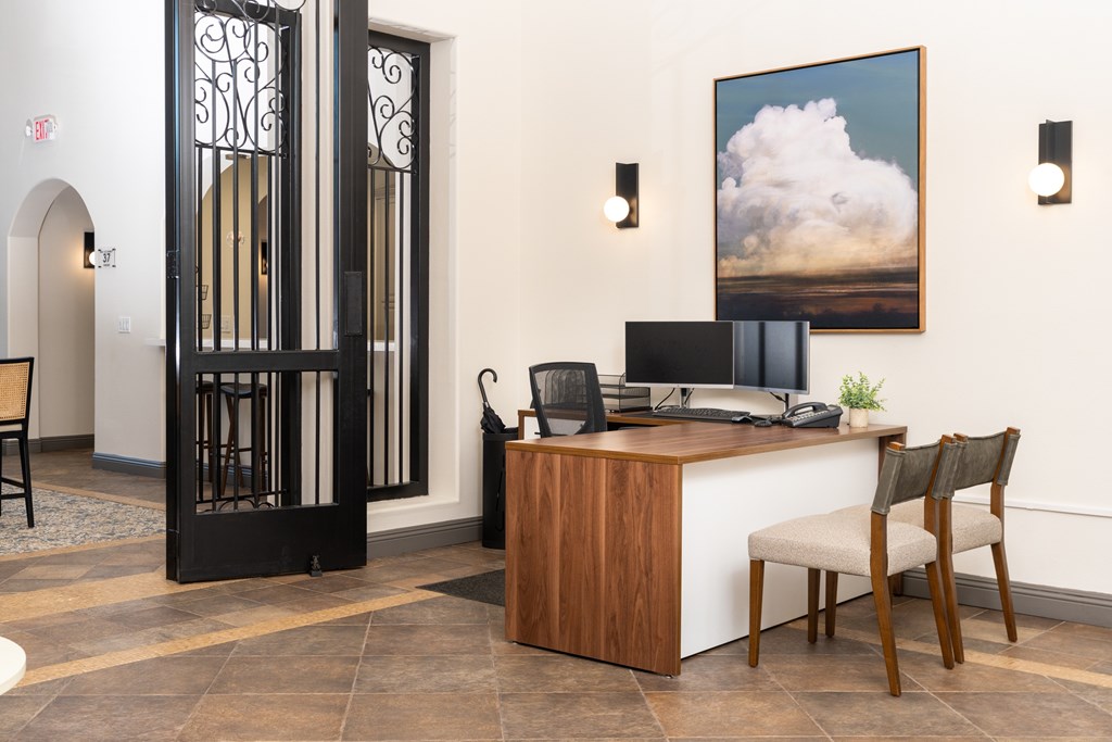 A room with a desk and a chair in front of a painting.