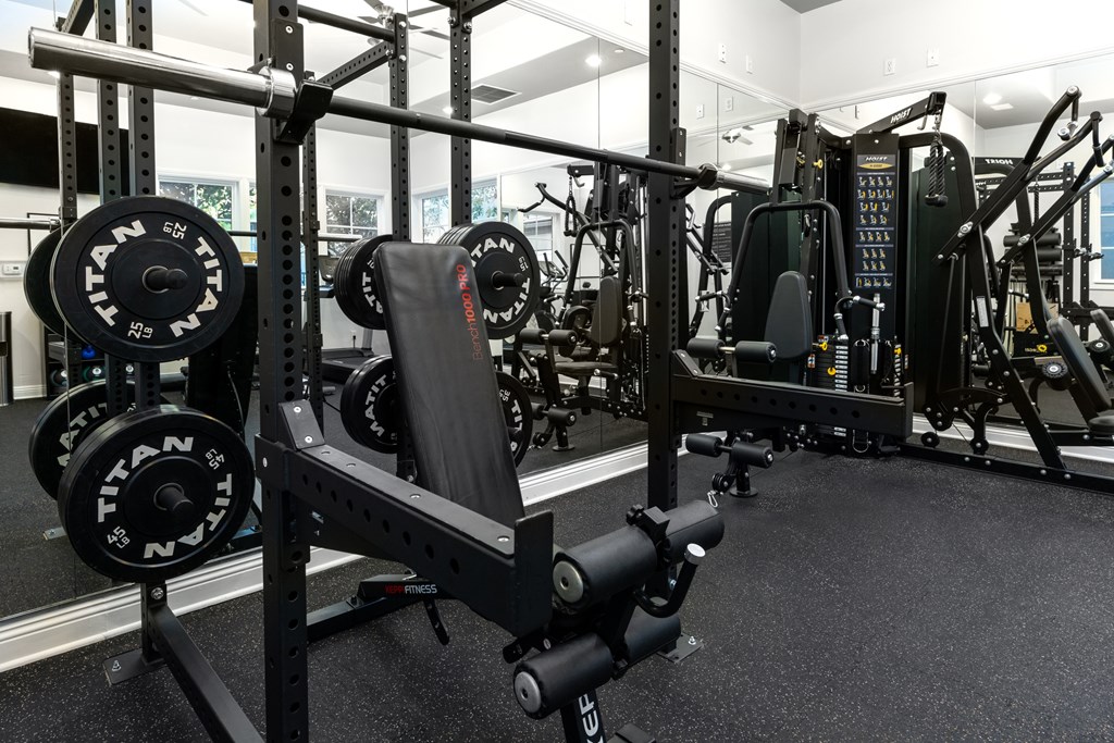 A gym with a squat rack and a weight bench.