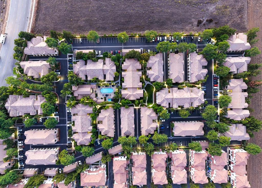 A bird's eye view of a residential area with houses and a pool.