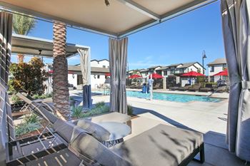 Cabana with lounge seating and a pool in the background.