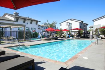 A swimming pool surrounded by lounge chairs and umbrellas.