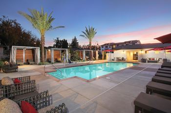 A poolside area with lounge chairs and palm trees.