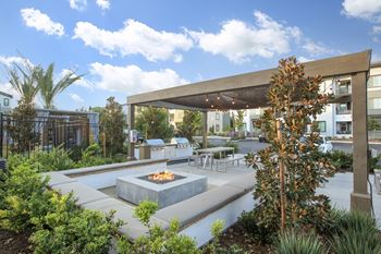 A fire pit is in the middle of a patio surrounded by plants.