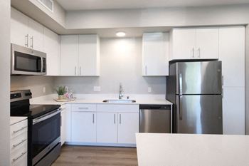 A modern kitchen with white cabinets and stainless steel appliances.