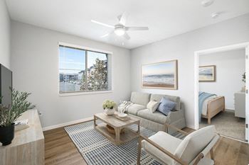 A living room with a grey couch, a coffee table, and a painting on the wall.