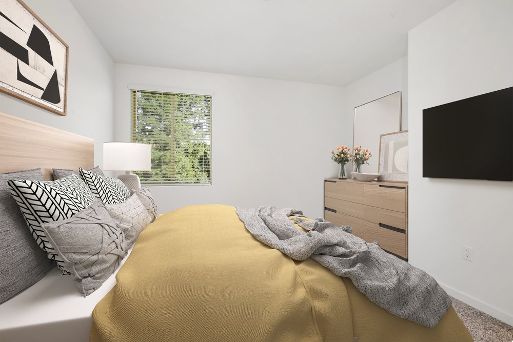 A bedroom with a bed covered in a yellow blanket and a white pillow.