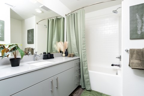 A bathroom with a white sink and green shower curtain.