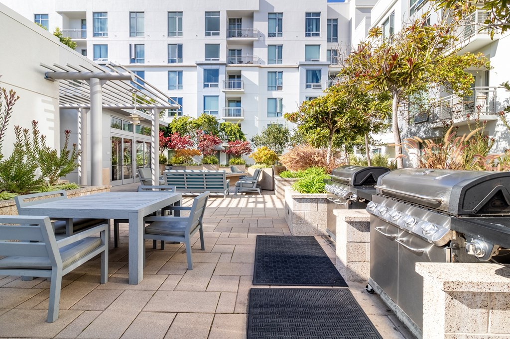 a patio with a table and chairs and a barbecue grill