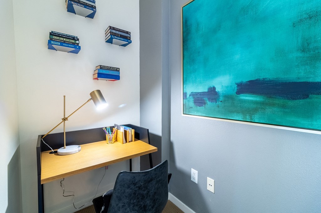 a desk with a lamp and a painting on the wall