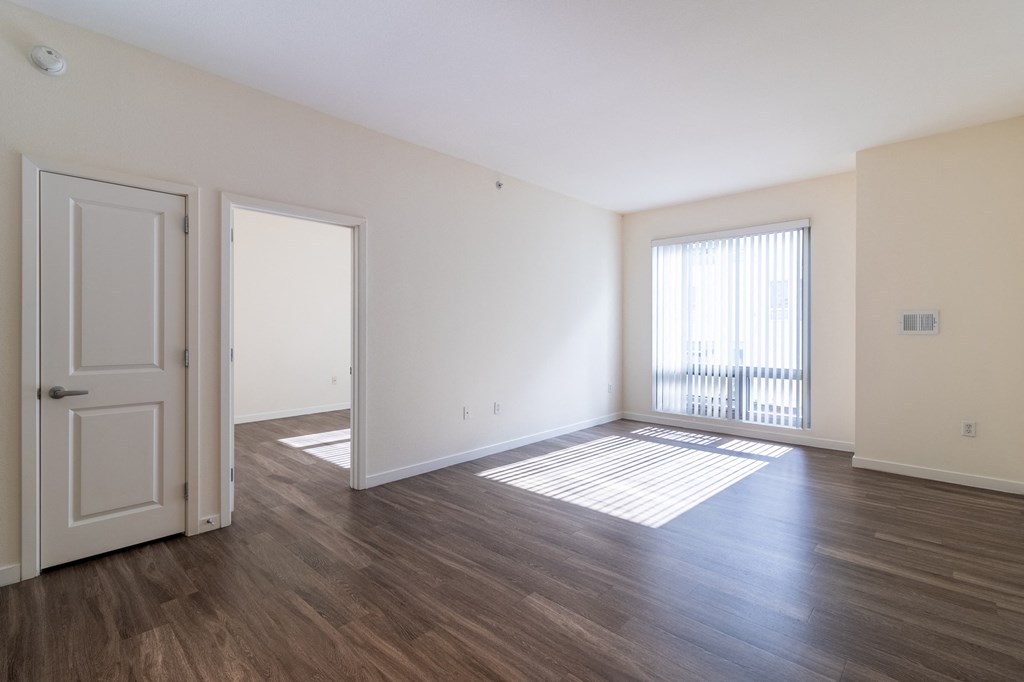 an empty living room with wood flooring and a window
