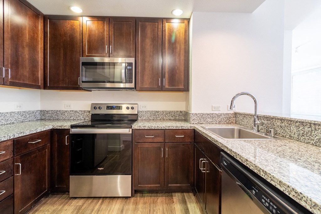 a kitchen with wooden cabinets and granite counter tops and stainless steel appliances