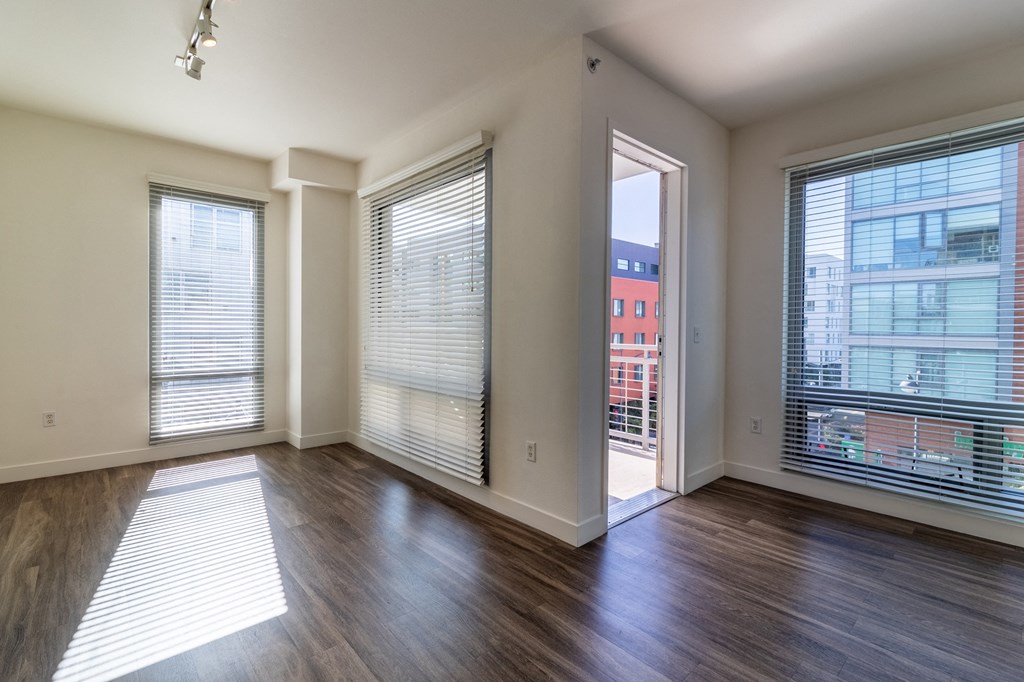 an empty living room with large windows and wood flooring
