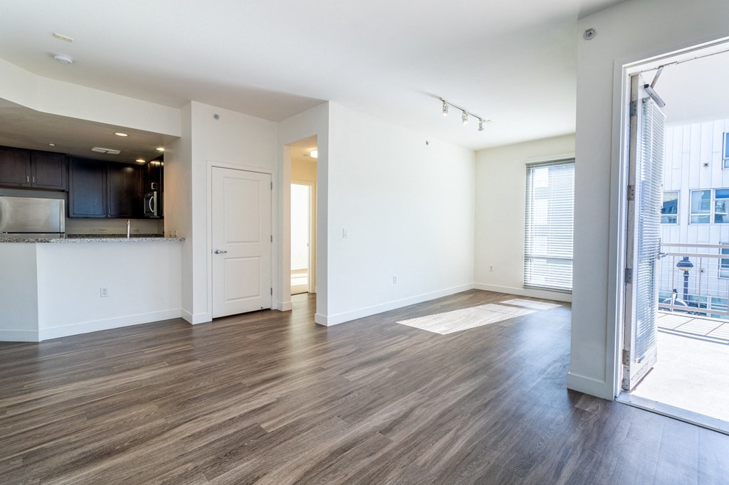 an empty living room and kitchen with wood flooring and a window