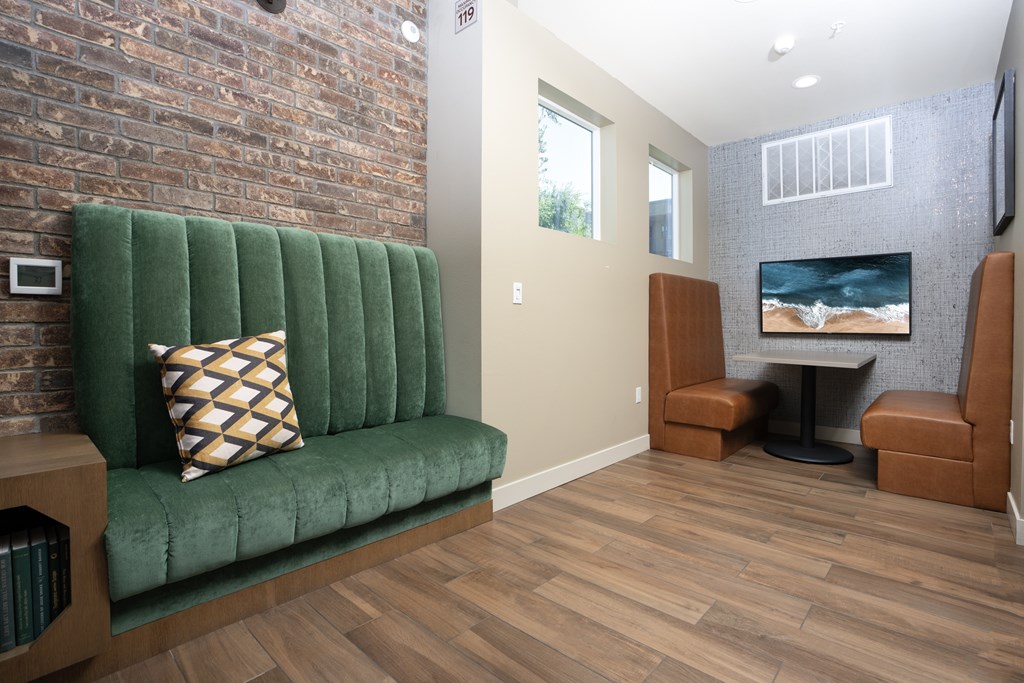 A living room with a green velvet couch and a television.