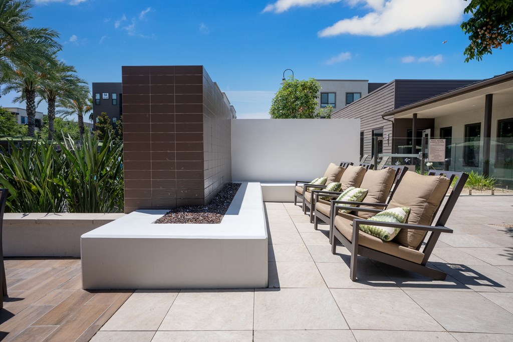 A modern patio with a fireplace and seating area.