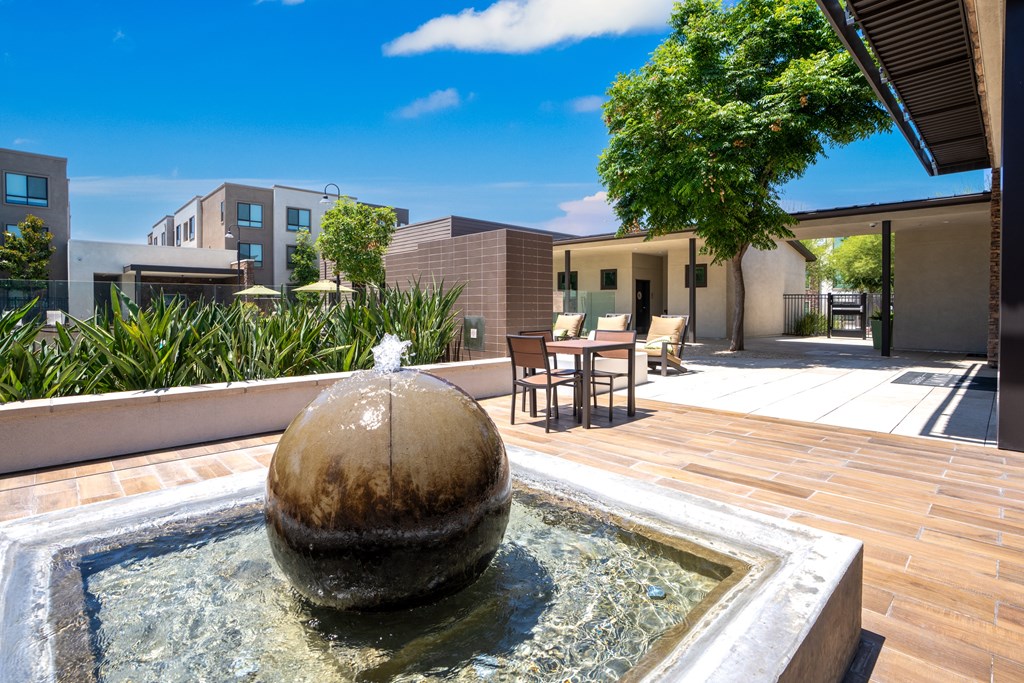 A fountain in the middle of a patio with buildings in the background.