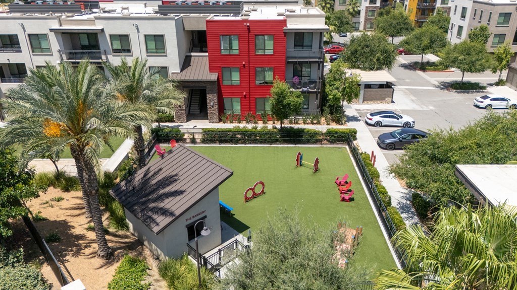 A red building is surrounded by palm trees and a green lawn.