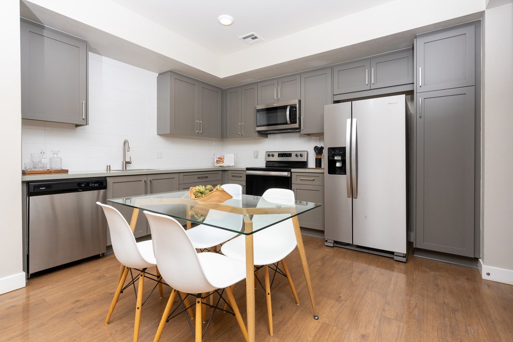 A modern kitchen with a glass table and white chairs.