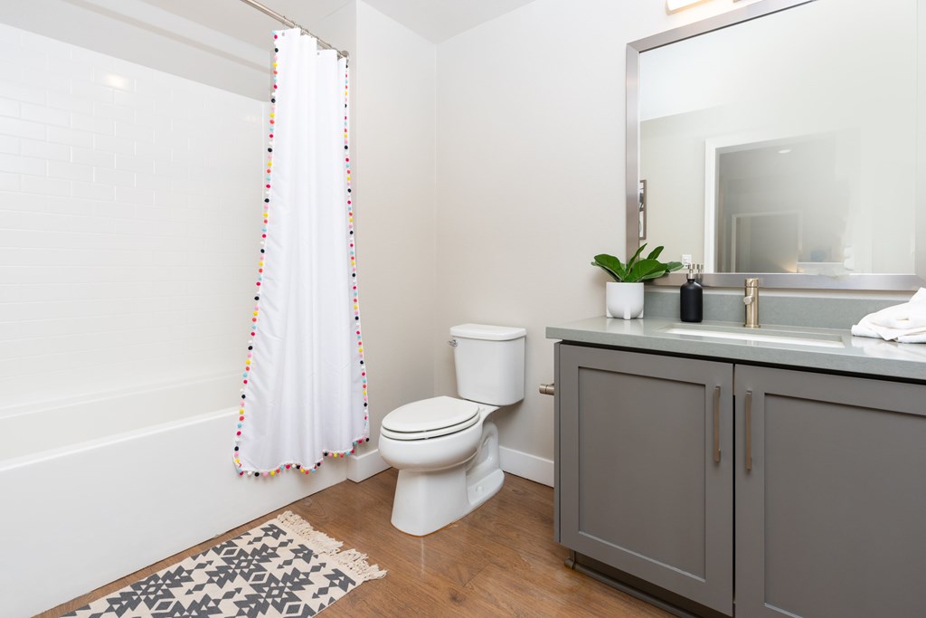 A white toilet sits in a bathroom next to a bathtub and a sink.