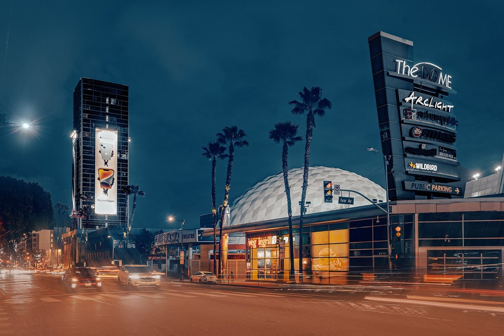 a city street at night with traffic and palm trees