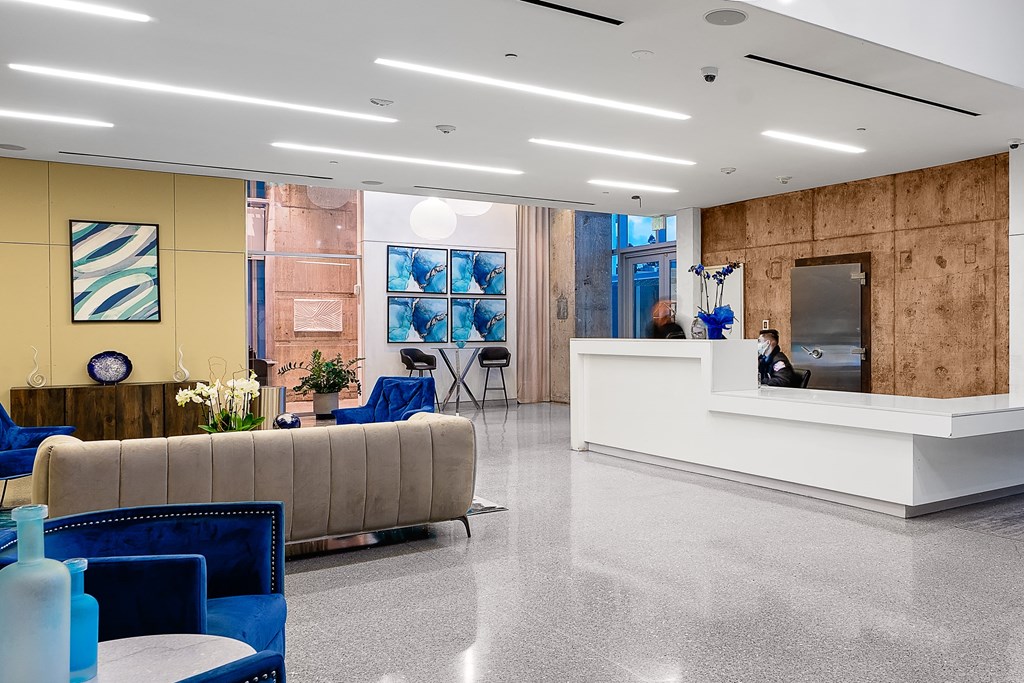 a view of the lobby with a reception desk and blue chairs