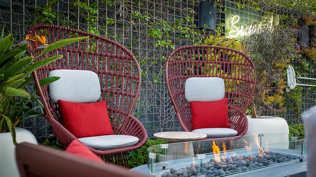 two chairs with red pillows are sitting next to a fire pit