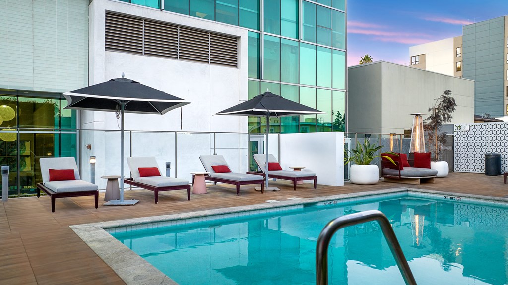 a swimming pool with chairs and umbrellas next to a building