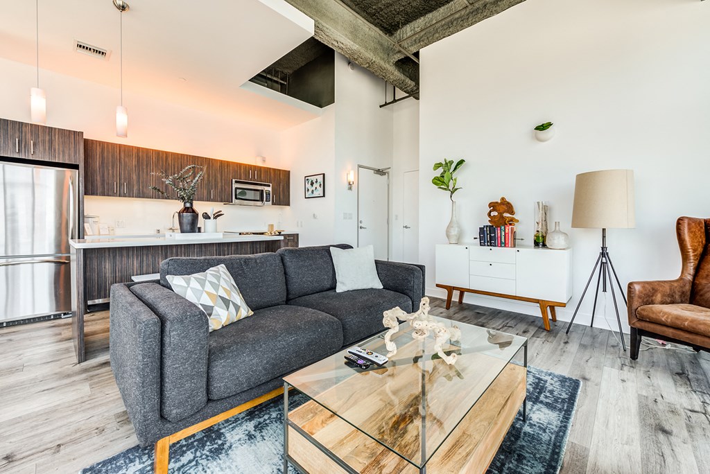 a living area with a sofa coffee table and a kitchen in the background