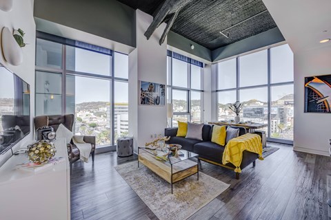 a living room with a black leather couch and a glass coffee table with a yellow blanket on