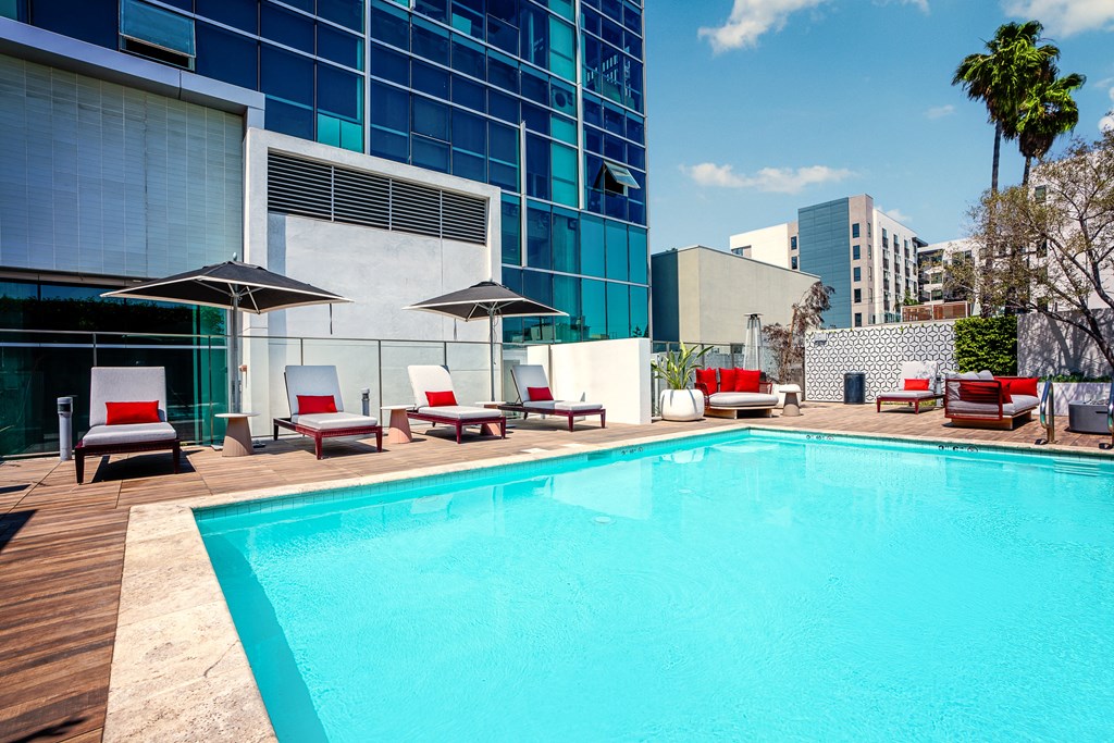 a swimming pool with deck chairs and umbrellas in front of a building