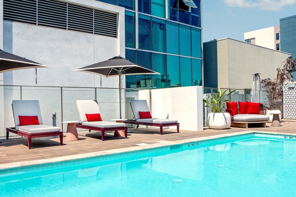 a hotel pool with deck chairs and umbrellas