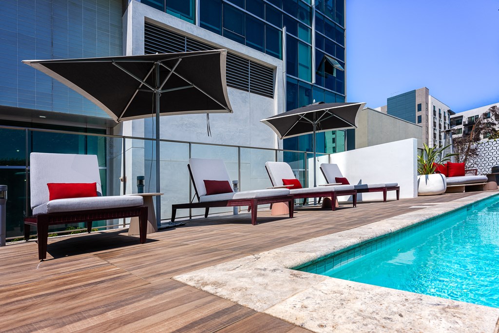 a poolside deck with lounge chairs and umbrellas