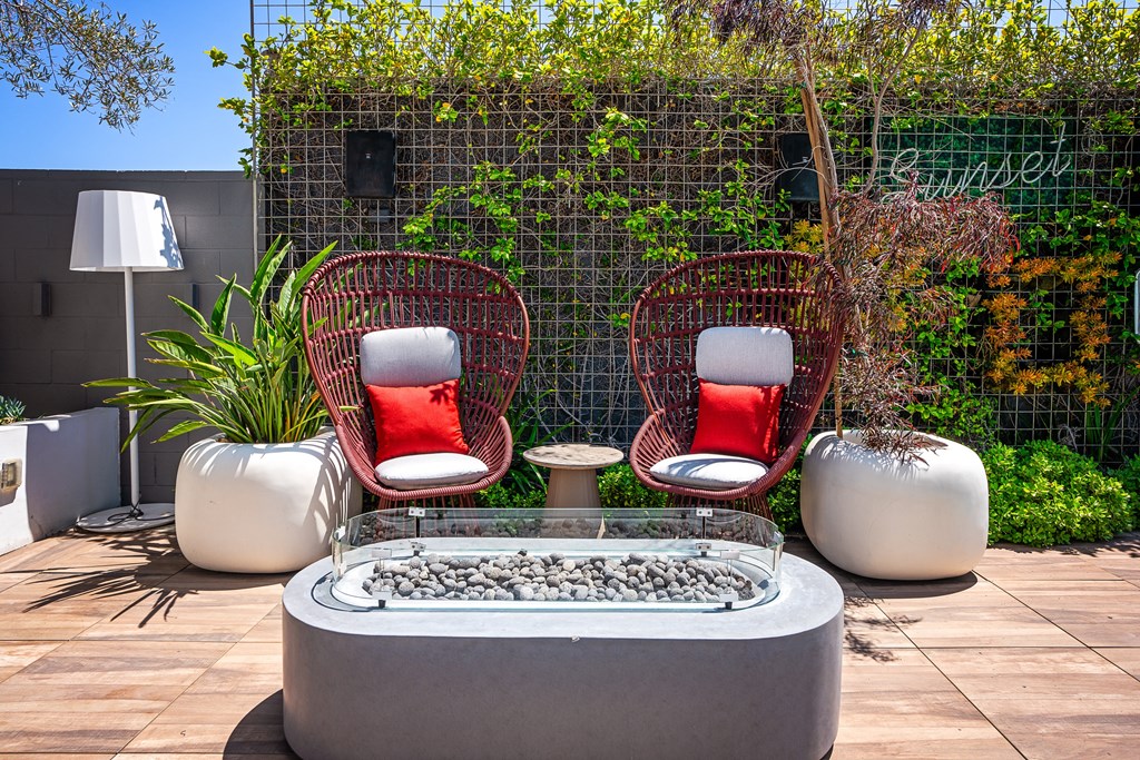 a courtyard with two wicker chairs and a fire pit