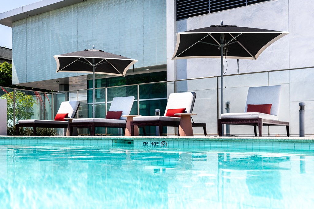 a hotel pool with chairs and umbrellas next to it