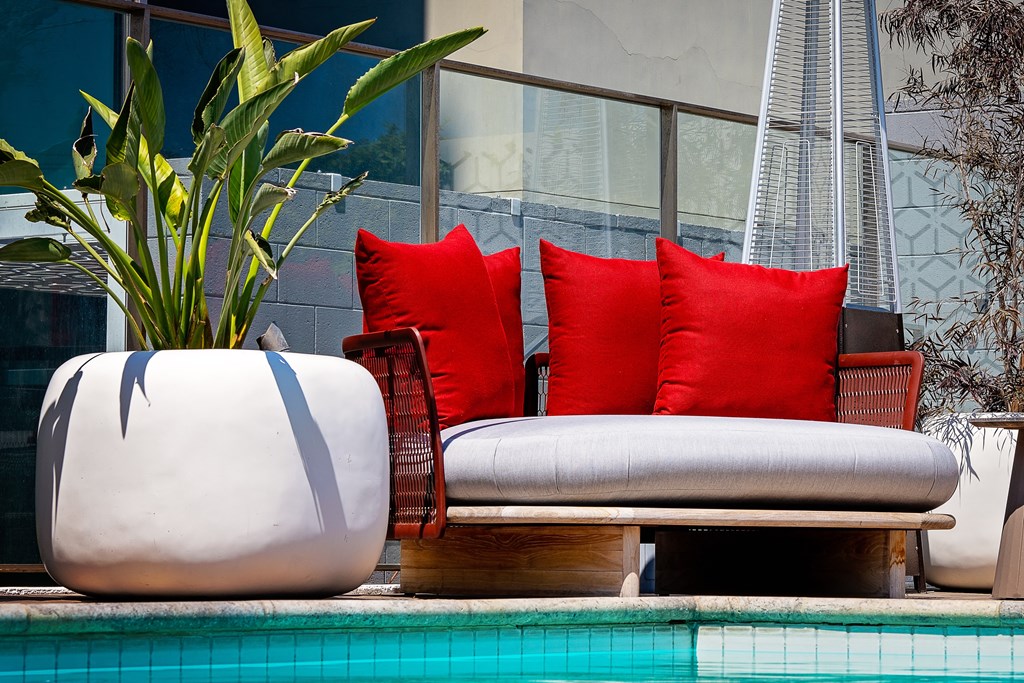 a chaise lounge next to a swimming pool with a potted plant