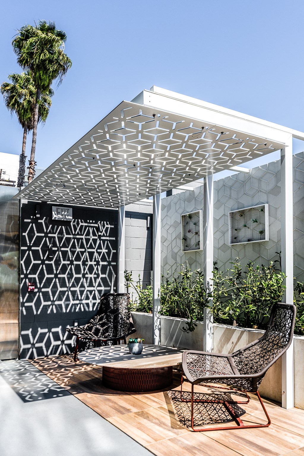 a pergola with two chairs and a table on a wooden deck