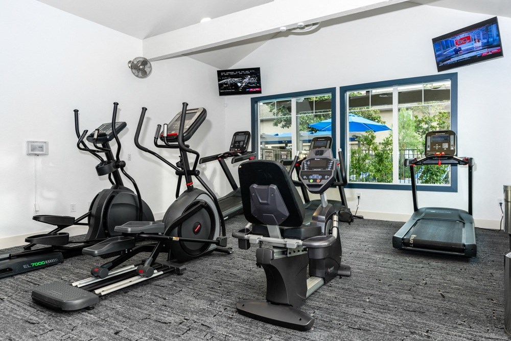 a gym with various cardio equipment in a room with windows at Sunstone Place, Riverside, CA, 92505