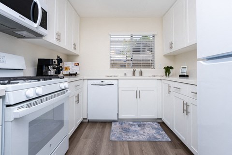 a kitchen with white cabinets and appliances and a window