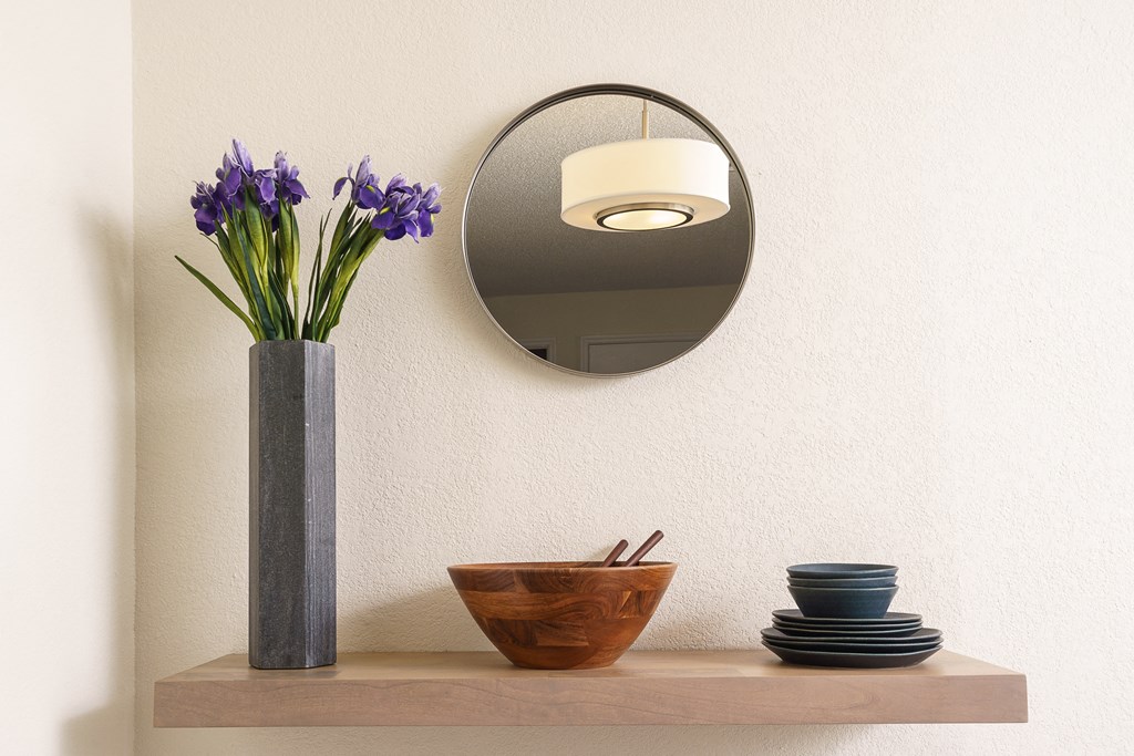 a shelf with a mirror and a vase with flowers on it at Sunstone Place, Riverside