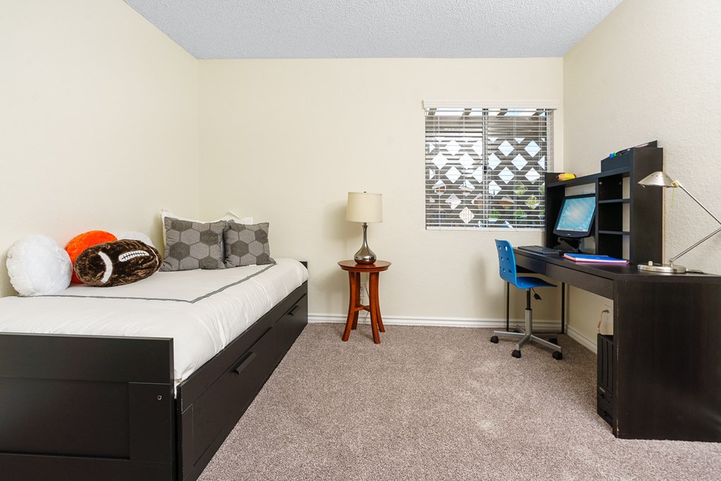 a bedroom with a bed and a desk with a computer at Sunstone Place, Riverside, California