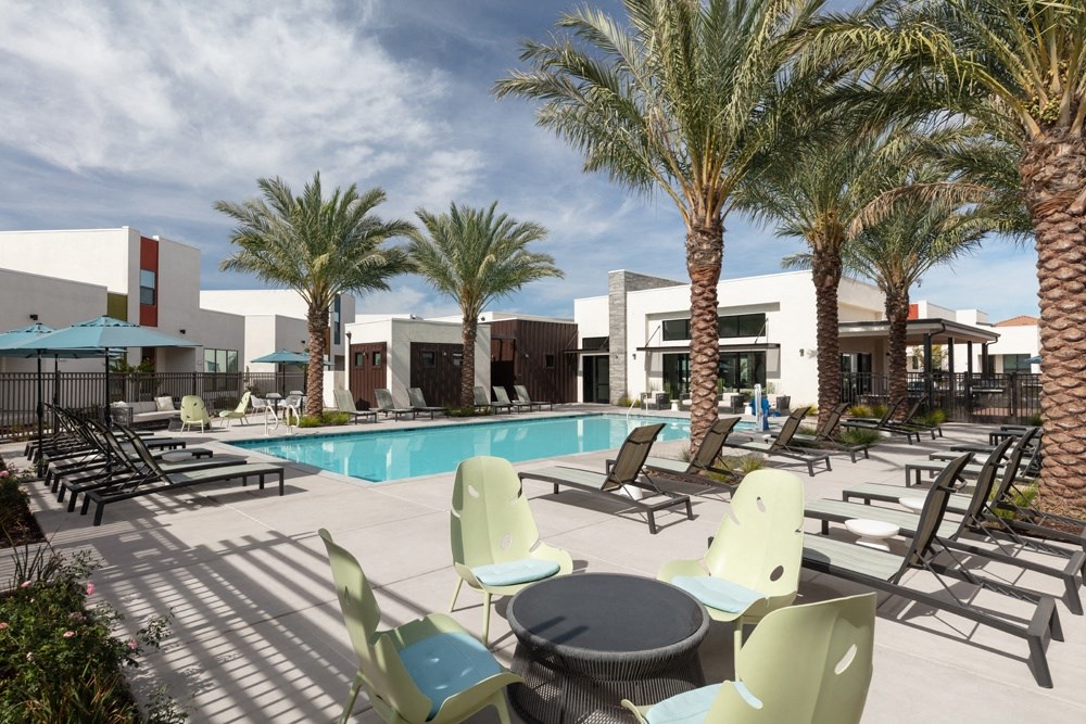 a swimming pool with chairs and tables and palm trees