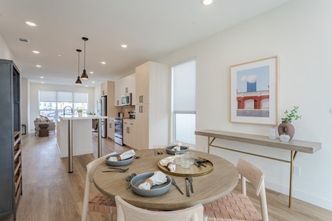 A modern dining room with a wooden table set for two.