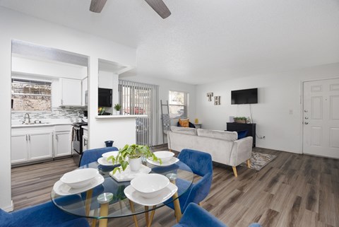 A modern living room with a glass table and blue chairs.