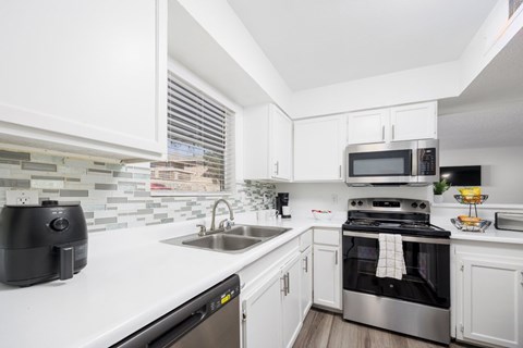 A modern kitchen with white cabinets and stainless steel appliances.