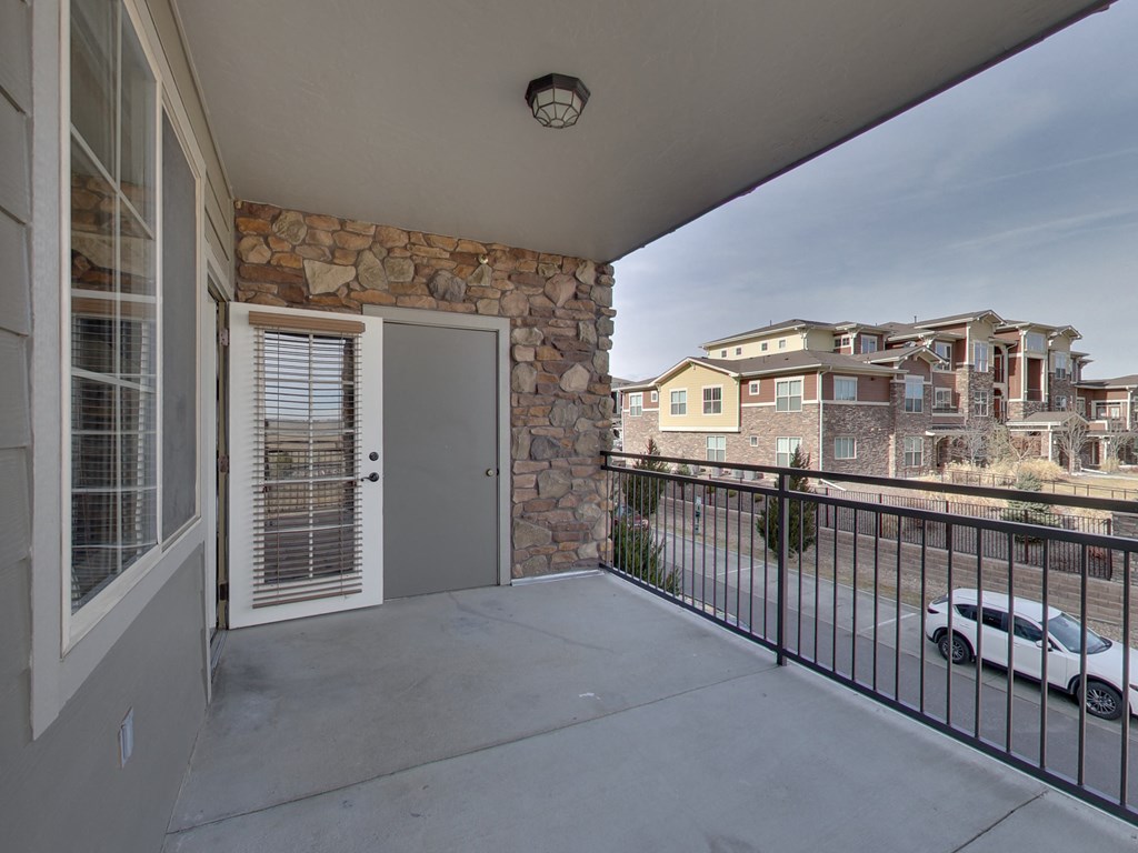 the view from the balcony of a condo with a door and a car parked outside