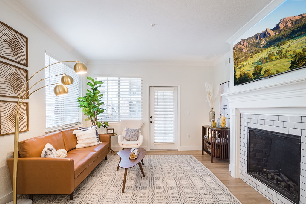 Living Room with Hardwood-Style Flooring, Area Rug, Couch, Armchair, Coffee Table, Floor Lamp, Fireplace, Wall Art, and Multiple Windows with Blinds at Terracina, Broomfield, CO 80020