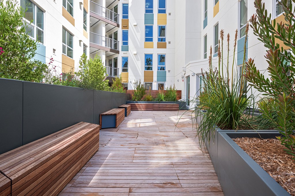 a courtyard with wooden benches and plants in an apartment building